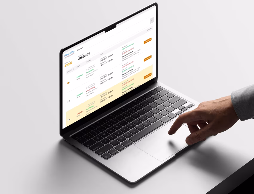 Laptop showing a Pparking dashboard with vehicle bookings and license plate tracking