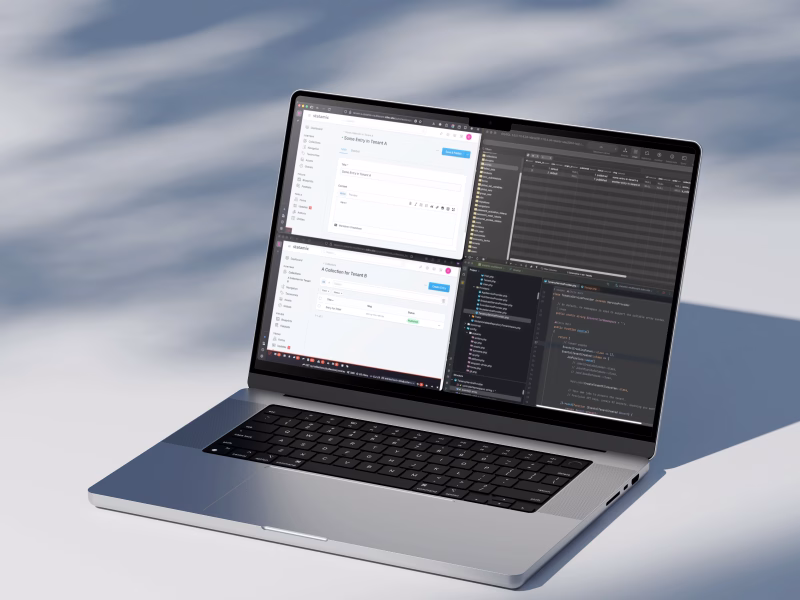 Laptop showing Statamic multi-tenant CMS setup with code editor and content management panels